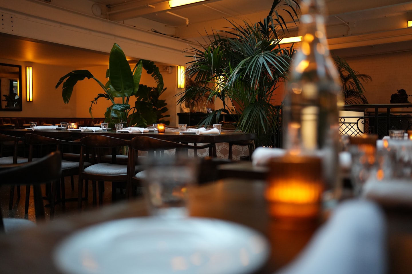 Drewniane stoły z nakryciami i świecami w przytulnej restauracji.