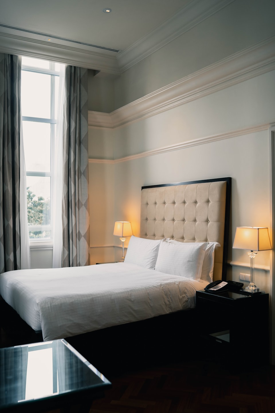 Pokój hotelowy z dużym łóżkiem i ciepłymi lampami.