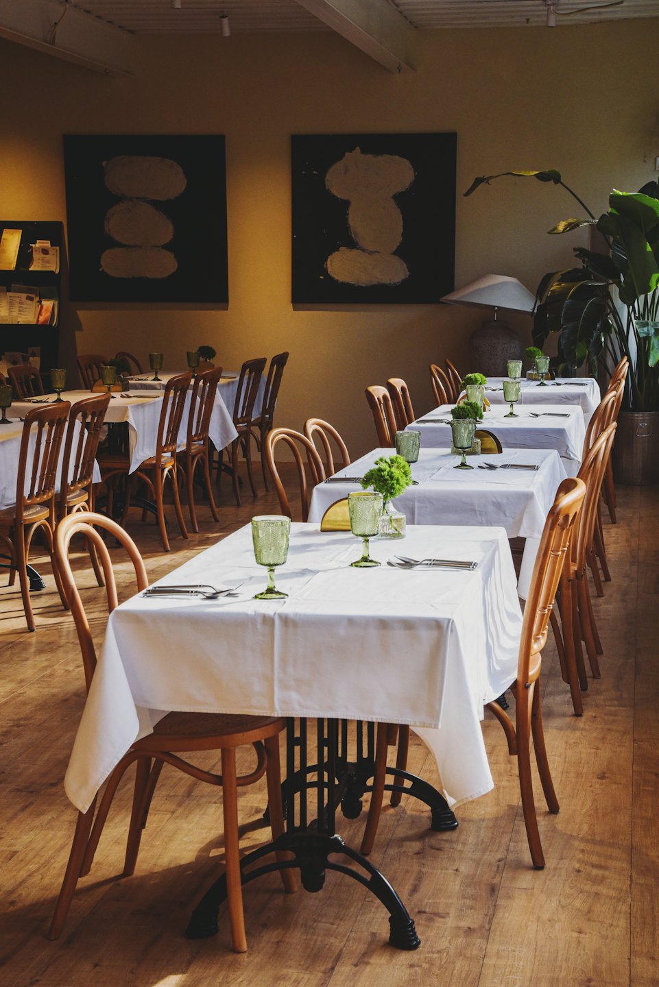 Stoliki restauracyjne z białymi obrusami i zielonymi kieliszkami w restauracji.
