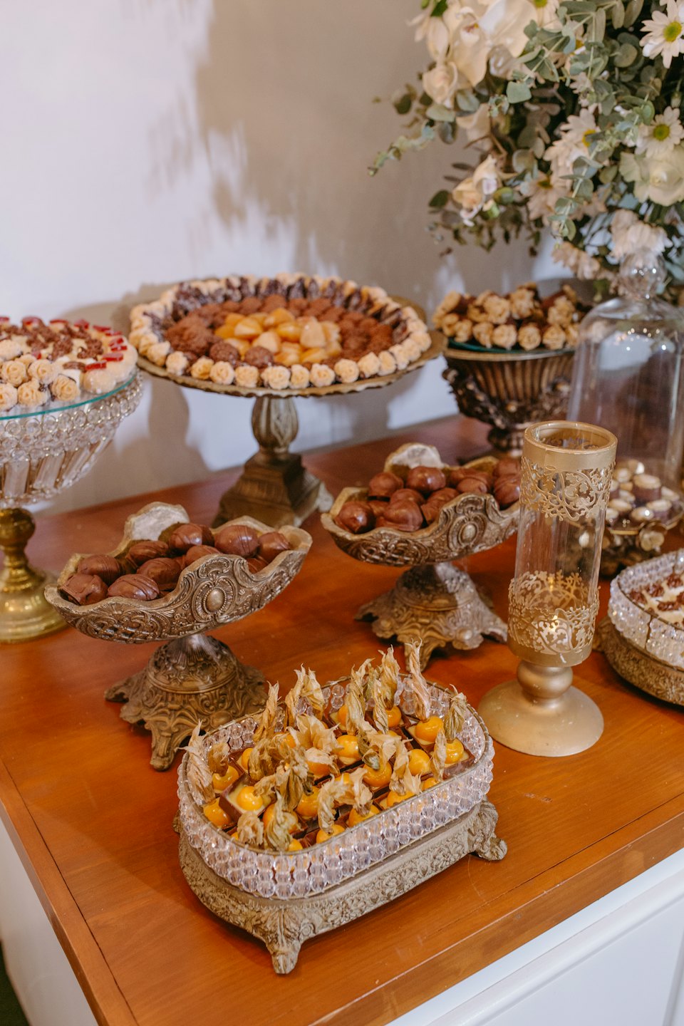 Eleganckie czekoladki i świeże owoce miechunki na ozdobnych półmiskach.